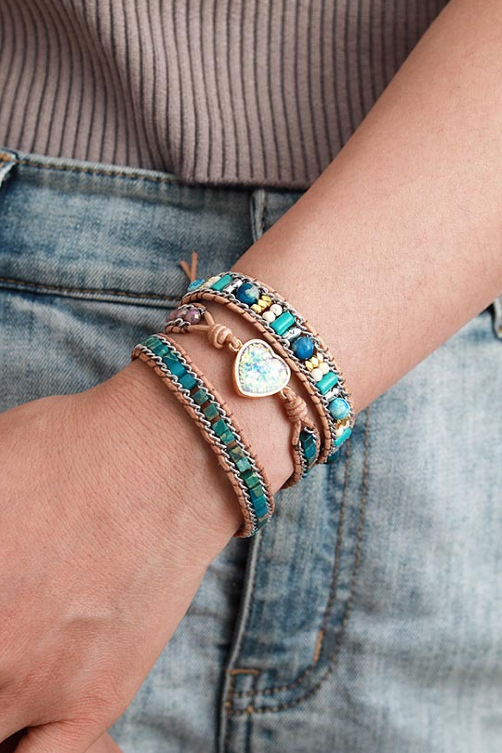 Layered natural stone bracelet worn on a wrist beside denim.