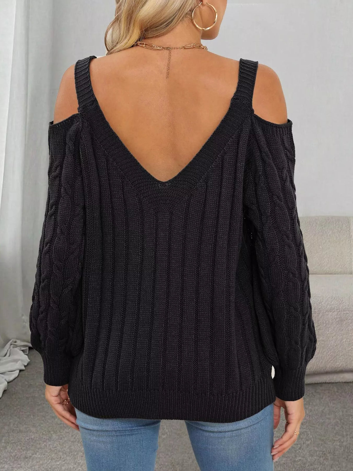 Back view of black cable-knit sweater showing V-shaped neckline and open shoulders