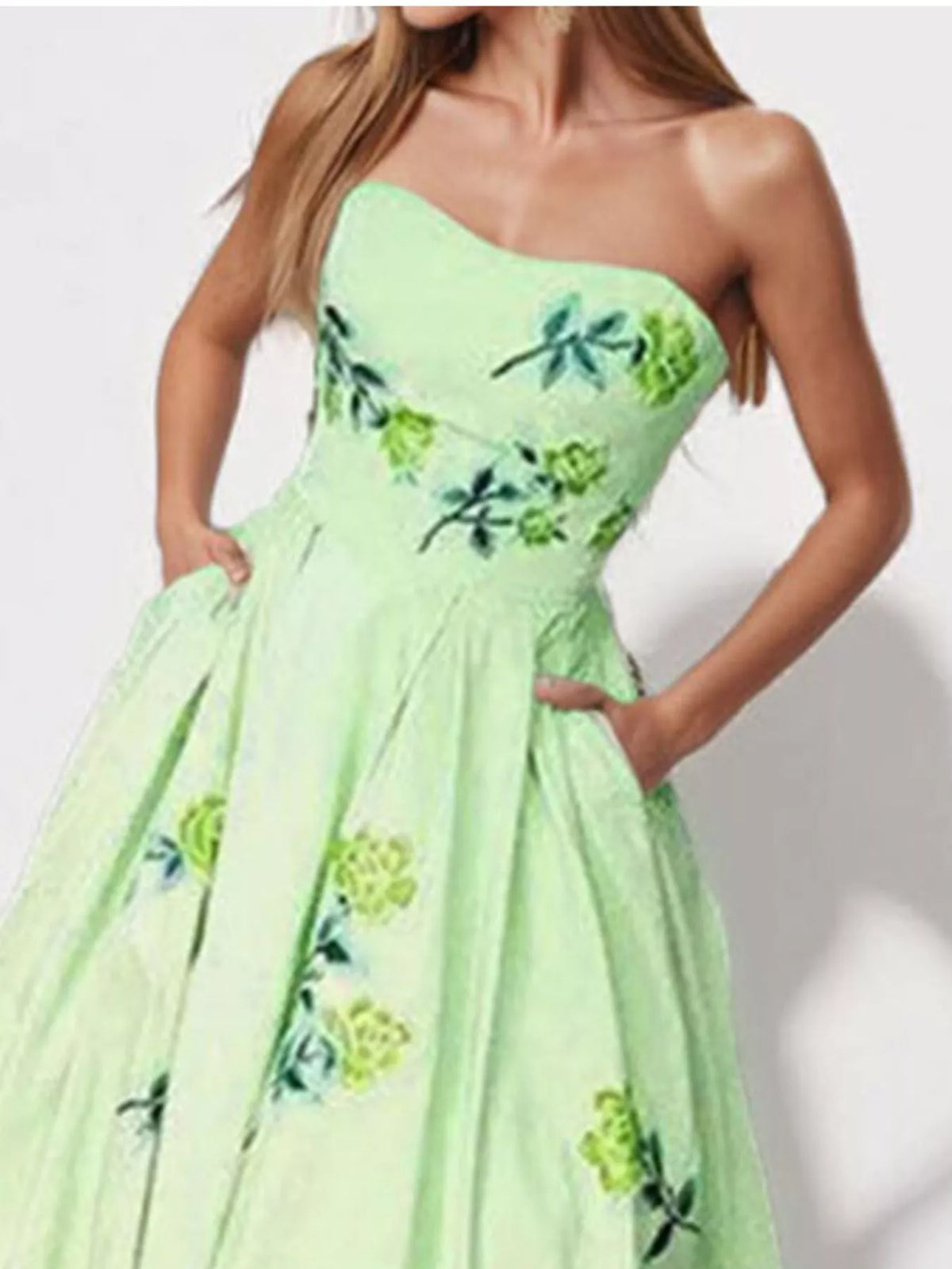 Close view of the light green strapless dress bodice with embroidered floral accents.