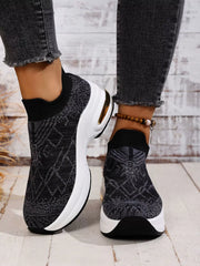 Black mesh platform trainers with one heel raised to show the side and sole