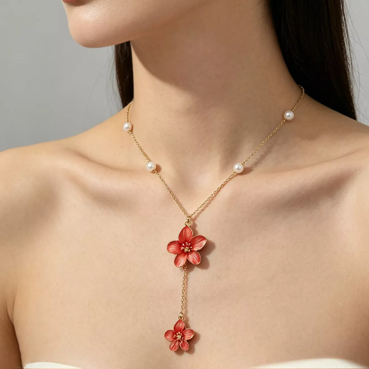 Side view of pearl-accented gold-tone necklace with two red flower pendants