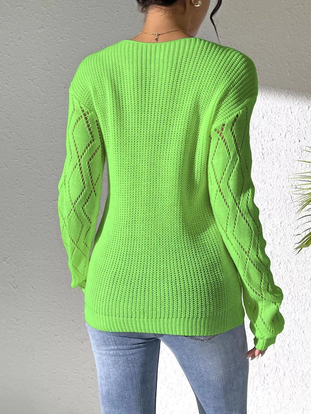 Back view of the bright green sweater showing openwork diamonds along the sleeves.