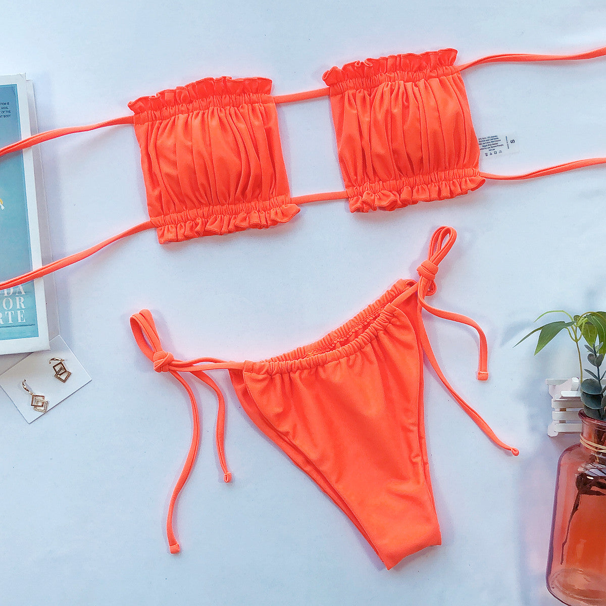 Orange ruched bandeau bikini and matching tie-side bottoms laid flat