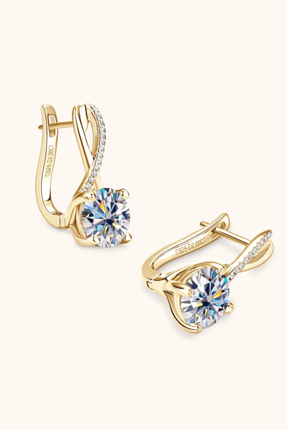 Angled view of gold-tone drop earrings with round clear stones and crossed loops
