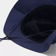 View beneath the navy bucket hat shows its interior and chin cord attachment.