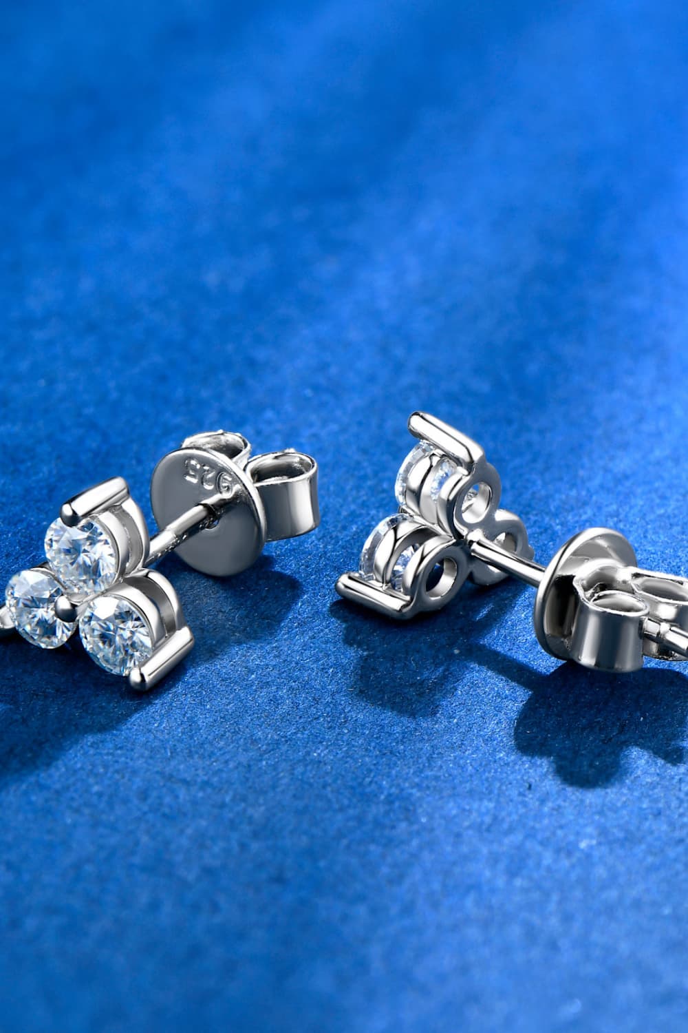 Silver-tone three-stone moissanite studs viewed from the side