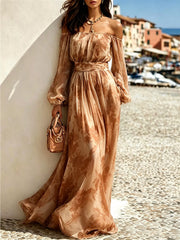 Brown patterned off-shoulder maxi dress with balloon sleeves modelled by the harbour
