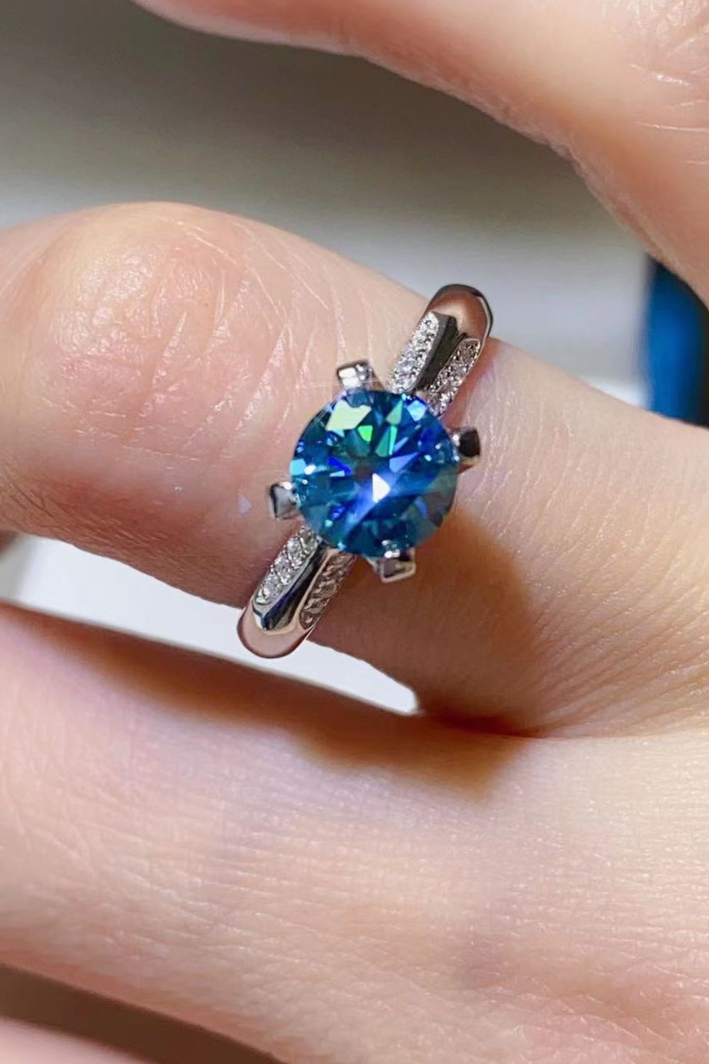 Angled view of sky-blue moissanite solitaire ring with four-prong setting