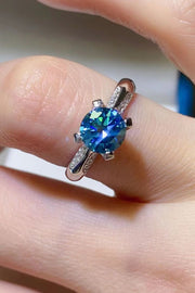 Angled view of sky-blue moissanite solitaire ring with four-prong setting