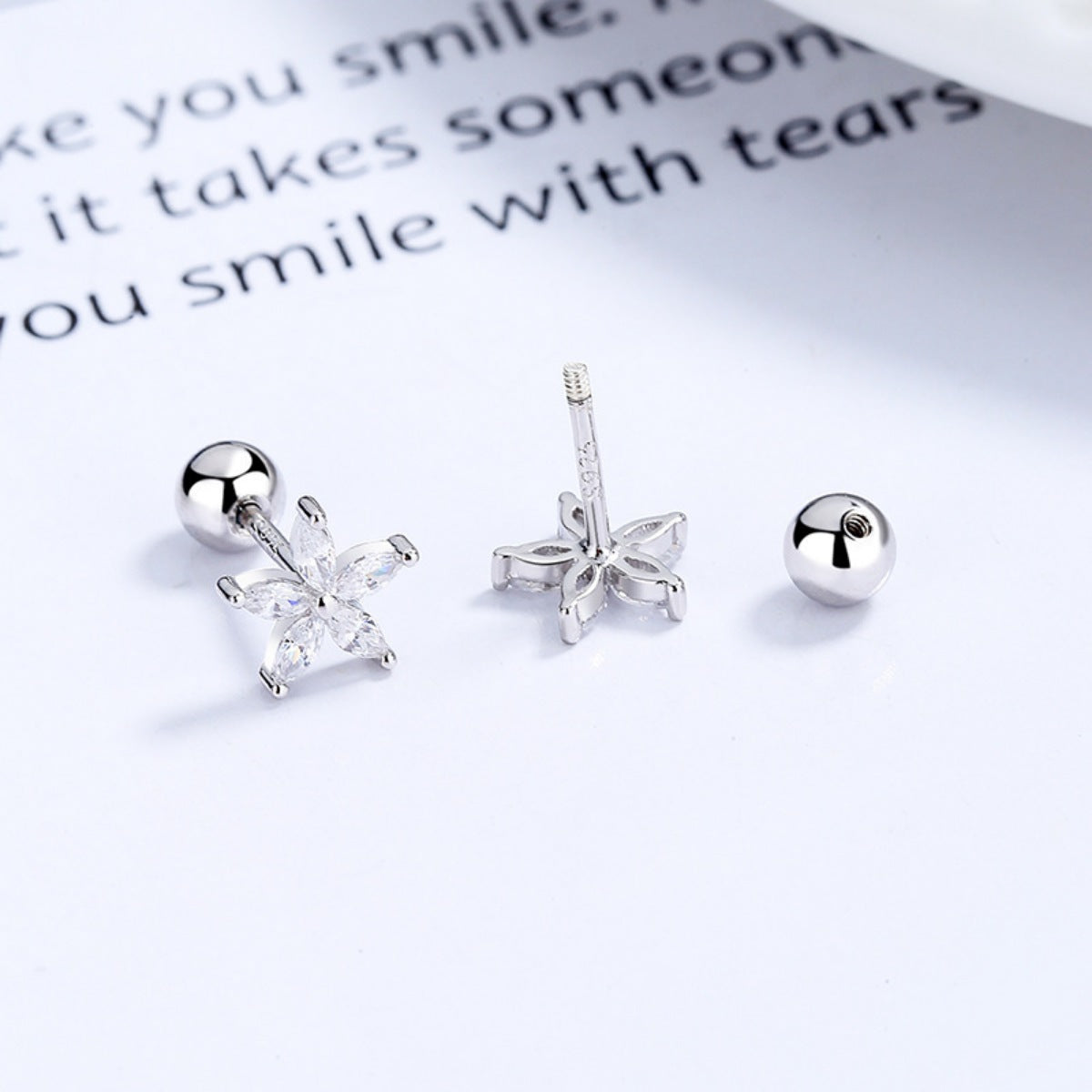 Backs of silver-tone flower stud earrings showing posts and ball backs