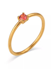 Gold-tone ring with red round stone worn on finger