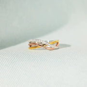Gold and silver-tone crossing bands of the 925 sterling silver ring on white fabric