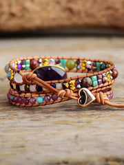 Close detail of the bracelet’s purple centerpiece, beads, and dangling heart charm.
