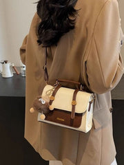 Two-tone flap crossbody bag worn over the shoulder with long strap