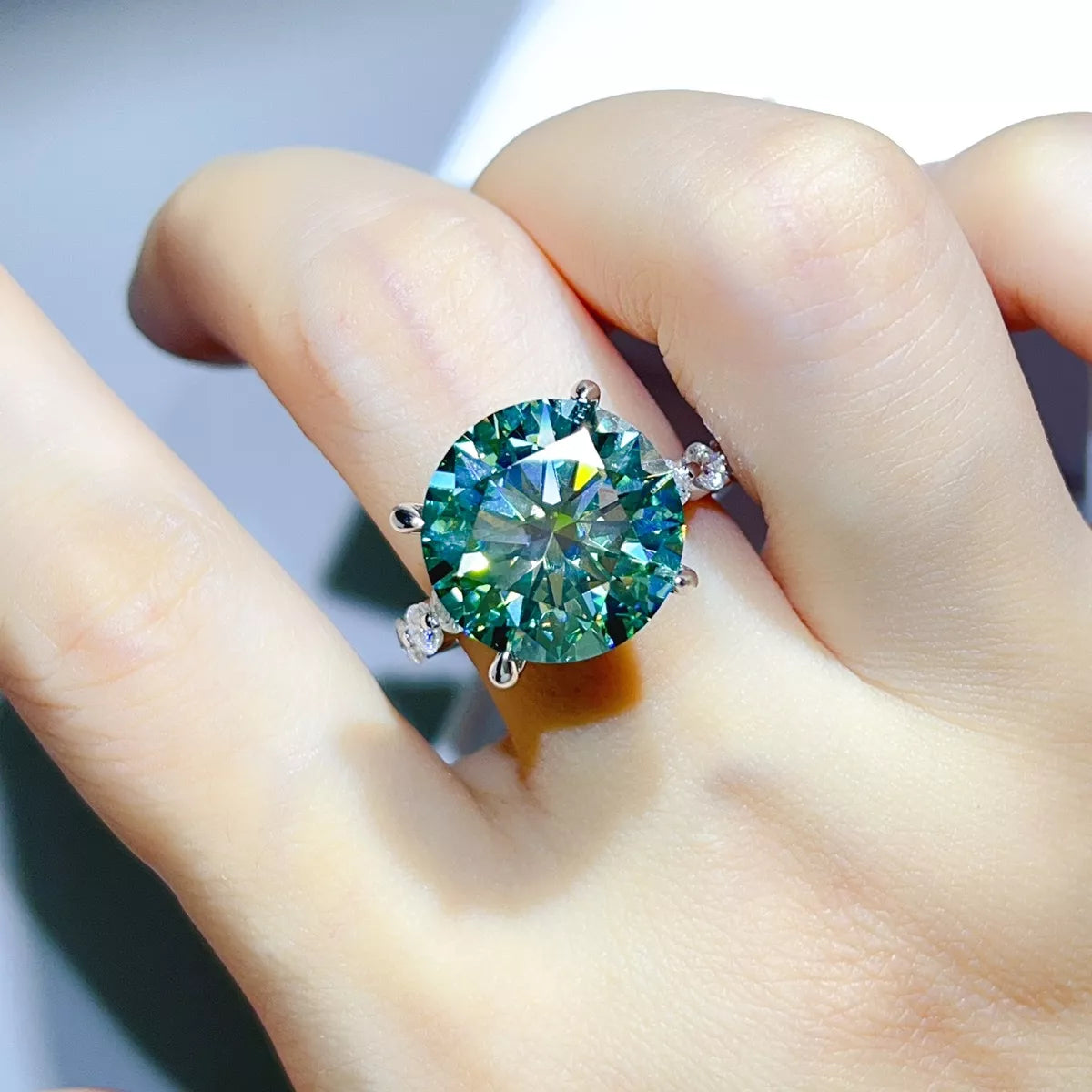 Green-blue ring worn on hand, showing silver setting