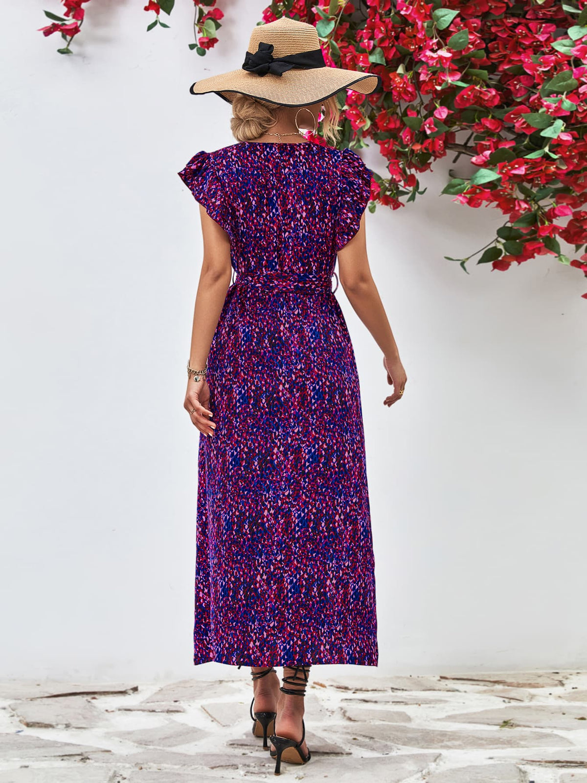Back view of purple printed flutter-sleeve dress with long skirt.
