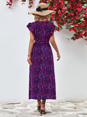 Back view of purple printed flutter-sleeve dress with long skirt.