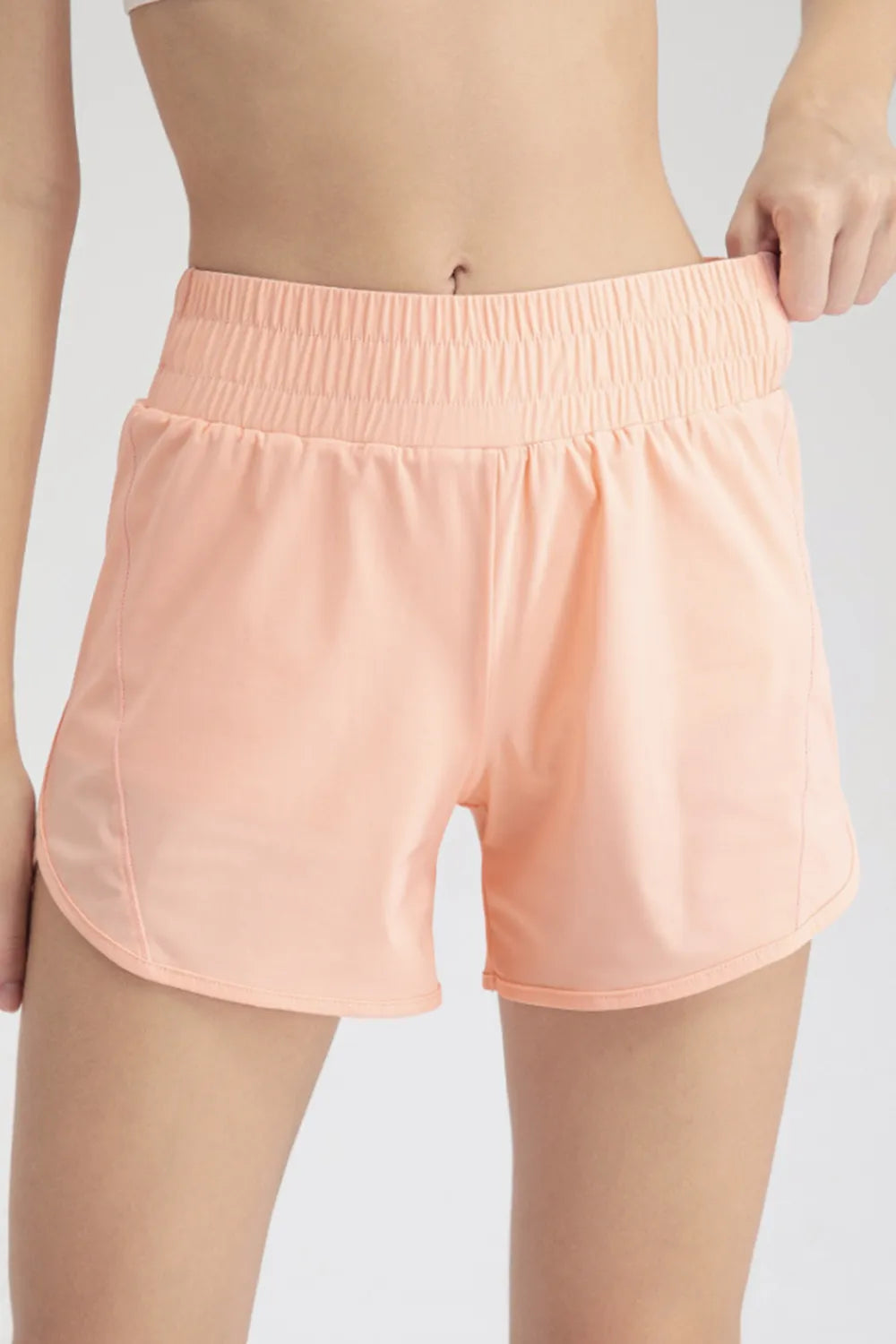 Close-up front view of peach active shorts with a wide gathered waistband
