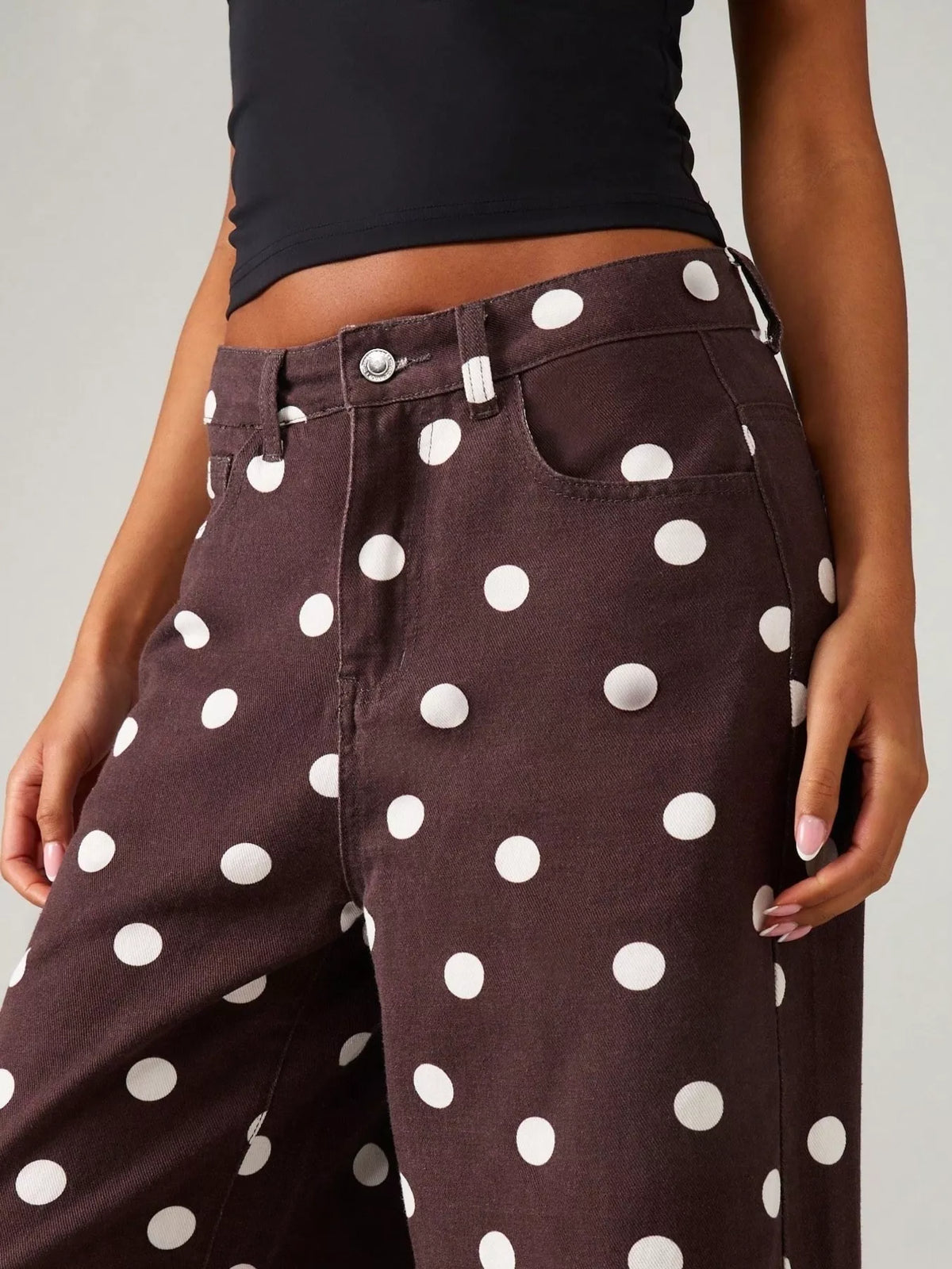 Angled close view of brown polka-dot pants and waistband
