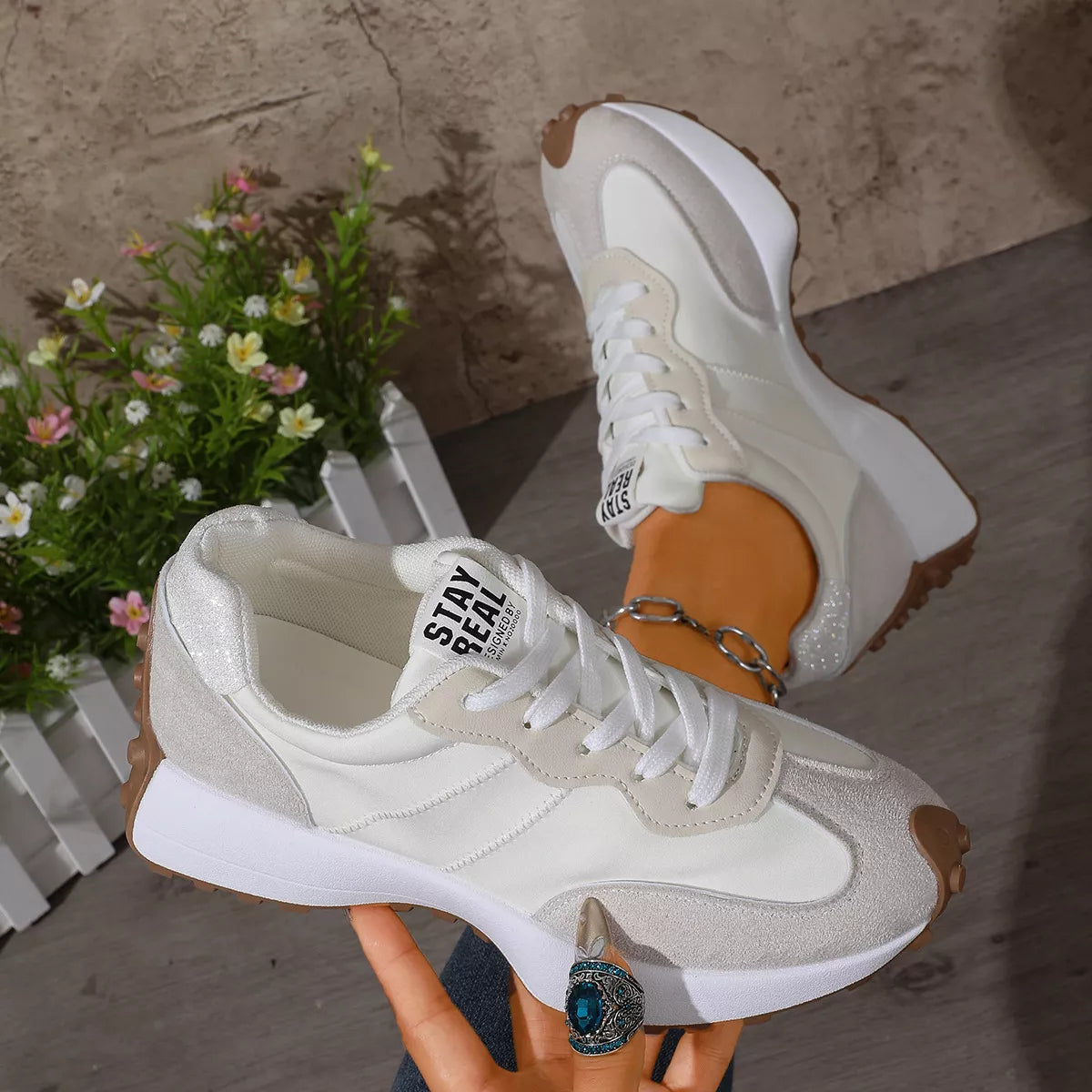 White low-top sneakers with black side panels held in hand