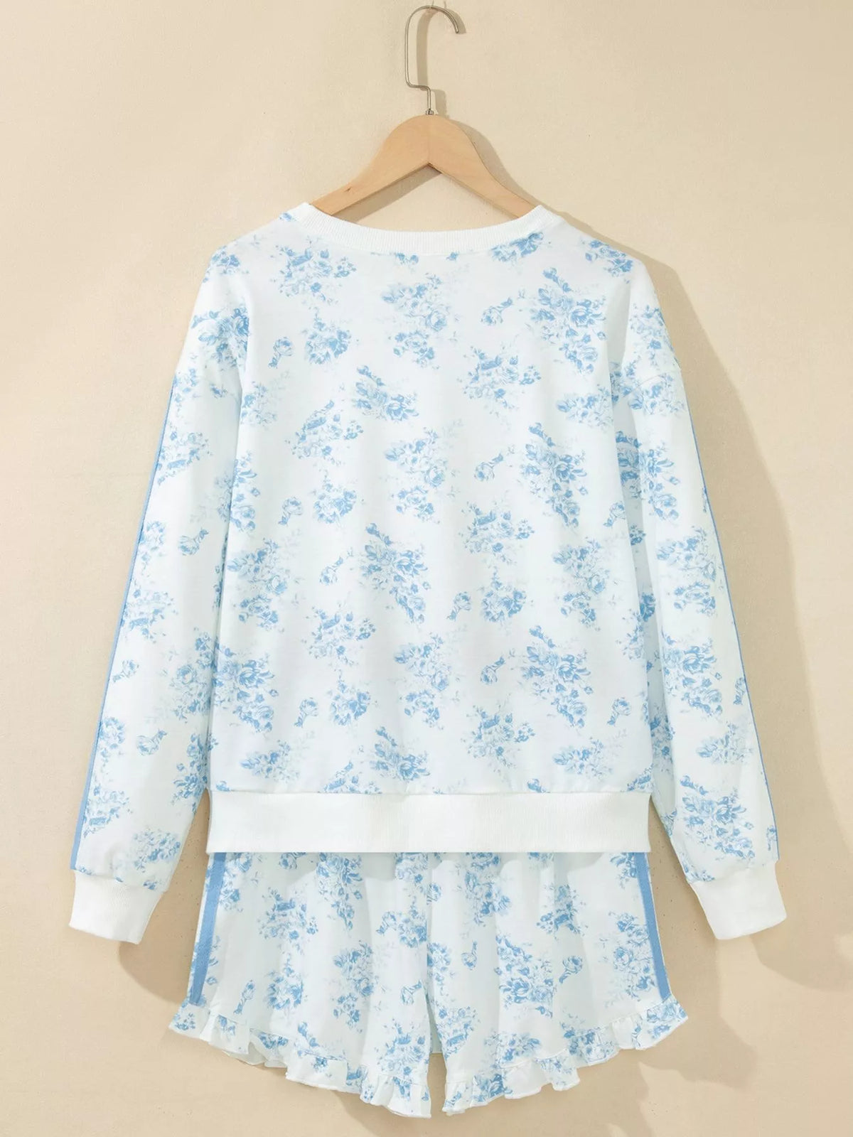 Back of white floral sweatshirt and matching shorts on a hanger