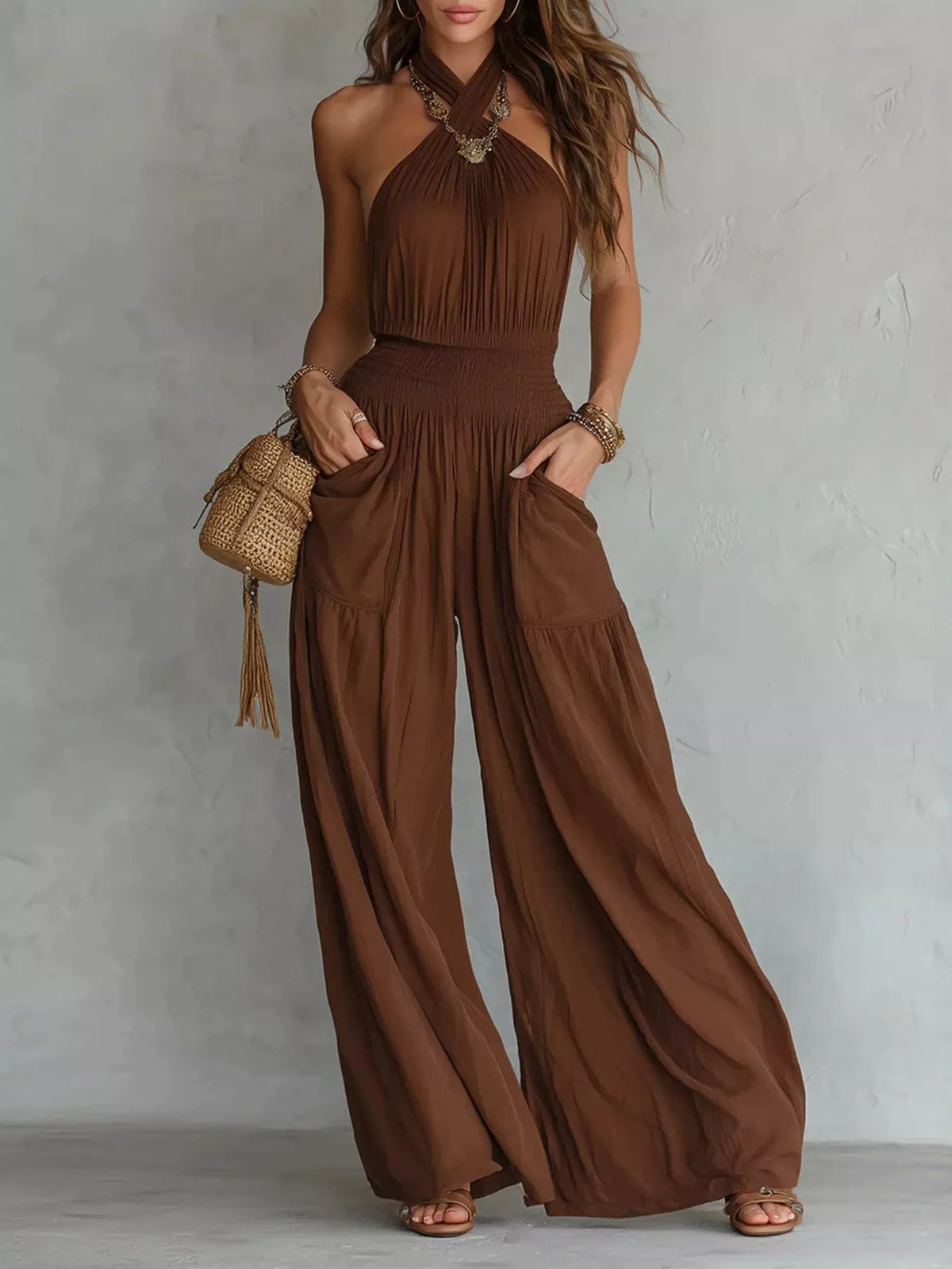 Front view of brown halter-neck wide-leg jumpsuit with smocked waist and pockets