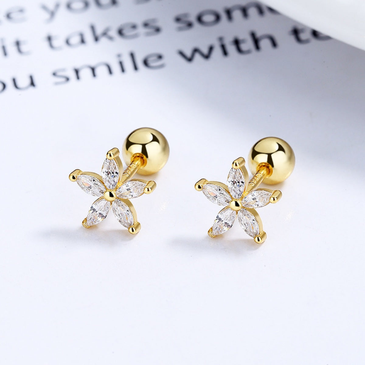 Pair of gold-tone flower studs with clear stones, angled view