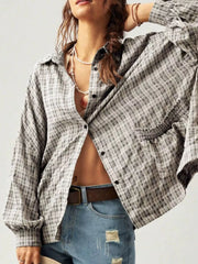 Gray plaid shirt worn open, showing its roomy sleeves and front buttons