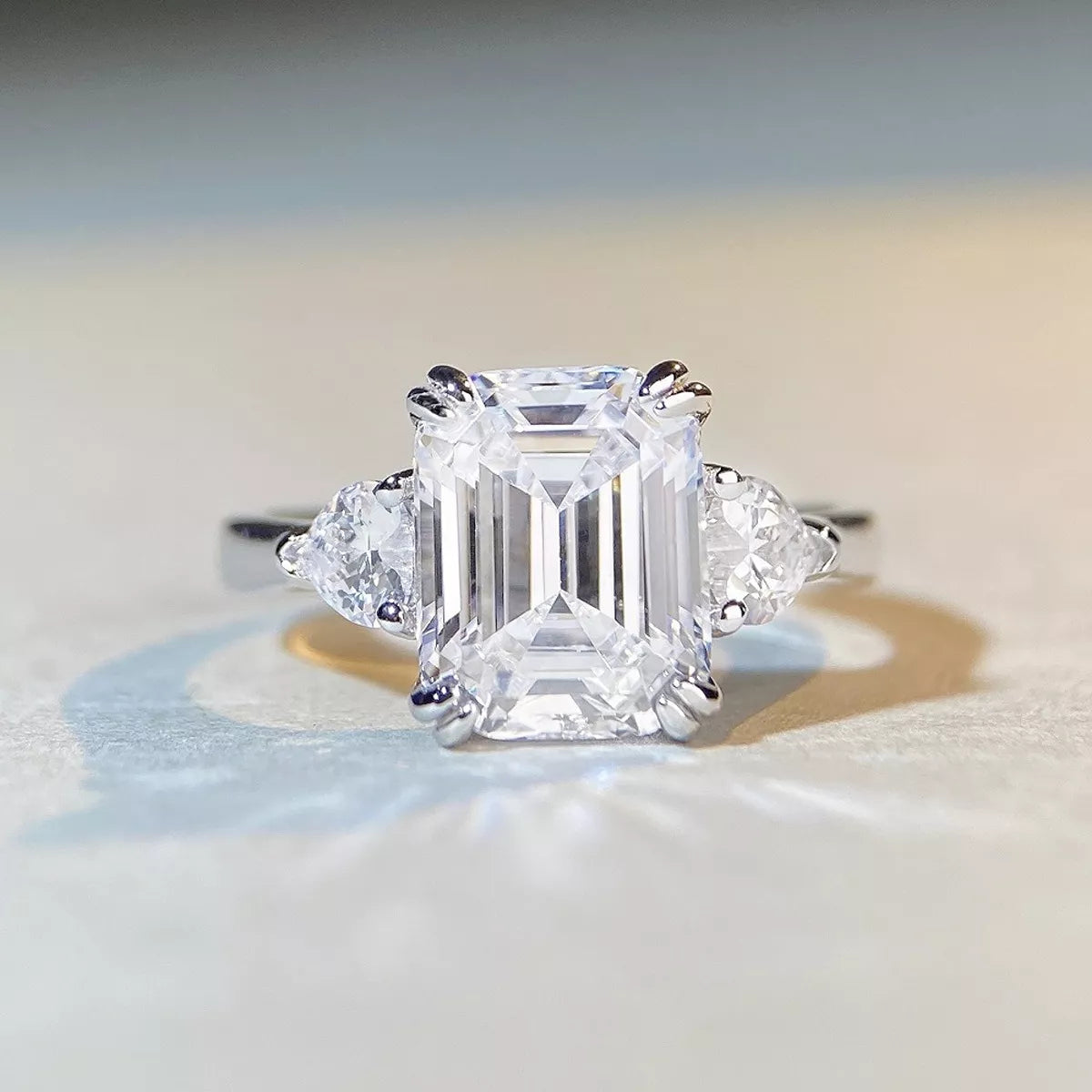 White-metal ring with a large clear emerald-cut center stone and two side stones, front view