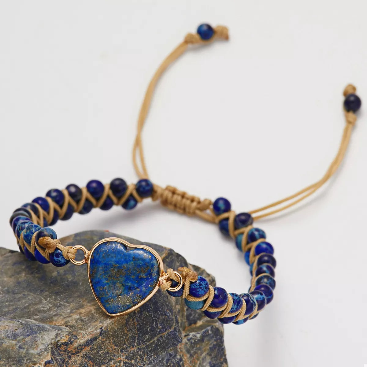 Blue heart beaded bracelet showing its gold-tone adjustable cords against a light background.
