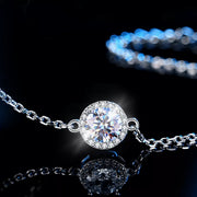 Macro view of the round moissanite centerpiece and silver chain against black