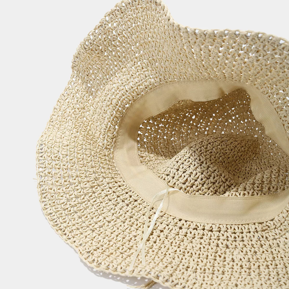 Underside of beige straw-woven sun hat showing the interior band