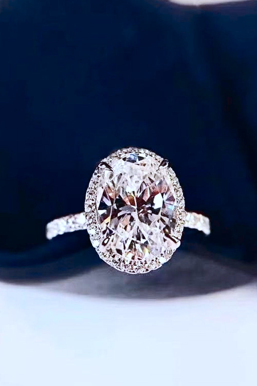 Front view of platinum-plated ring with clear oval moissanite and a pavé band