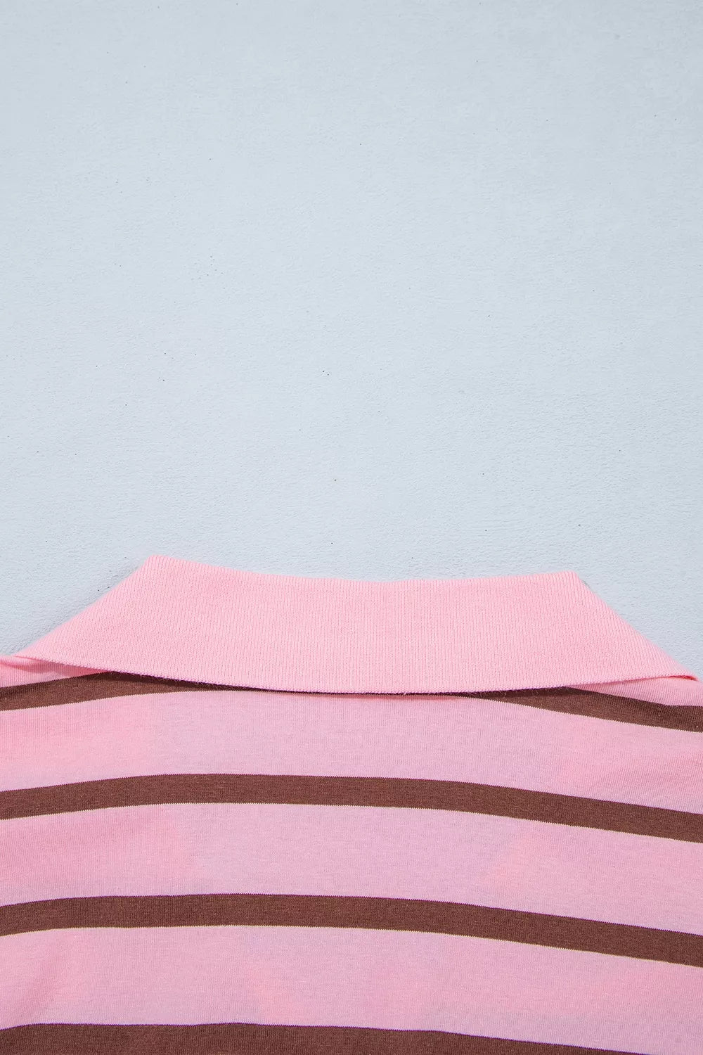 Close-up of the shirt hem and horizontal pink-brown stripes.