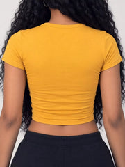 Golden yellow crew-neck crop T-shirt worn with dark pants, back view.