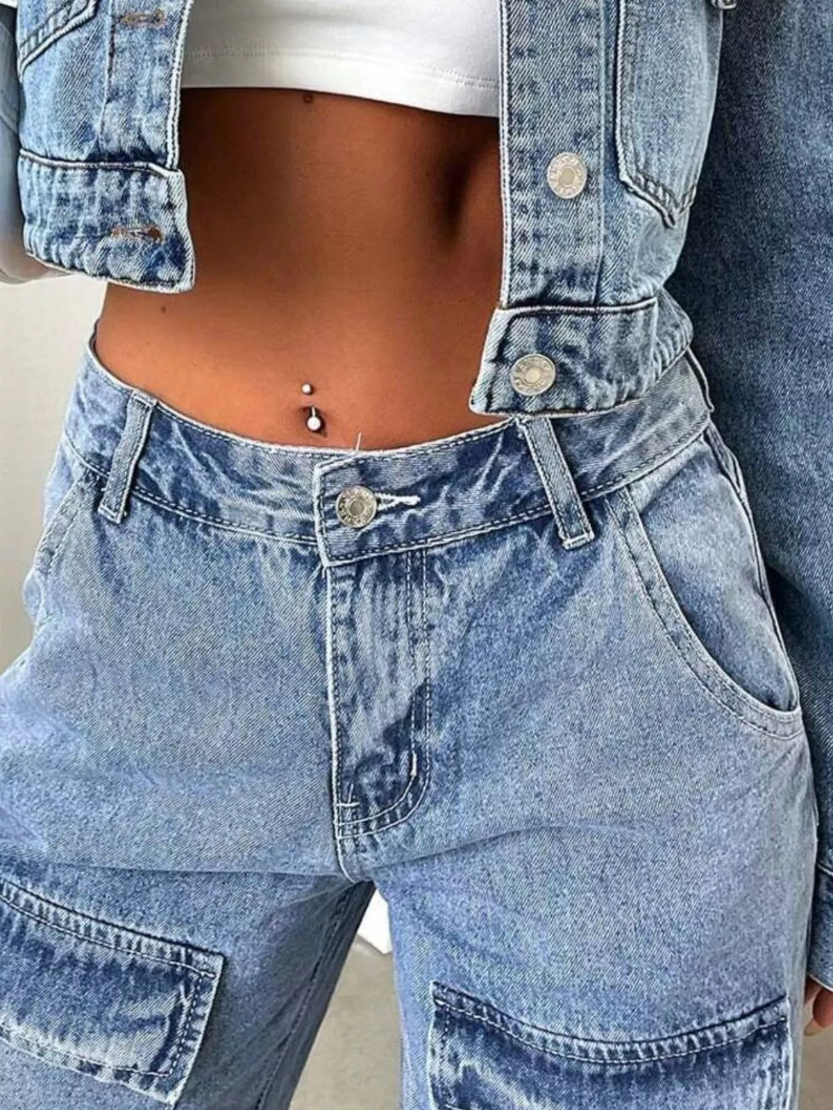 Close-up of light-wash cargo jeans waistband, button and thigh pocket
