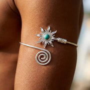 Silver-tone sunburst cuff bracelet with turquoise center worn on a wrist