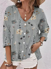 Model wearing gray floral V-neck button-down blouse with white shorts.