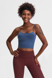Model in a blue cami and burgundy leggings, hands on hips.