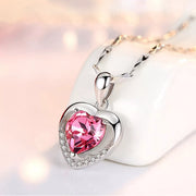 Silver-tone heart necklace with pink center stone on white background