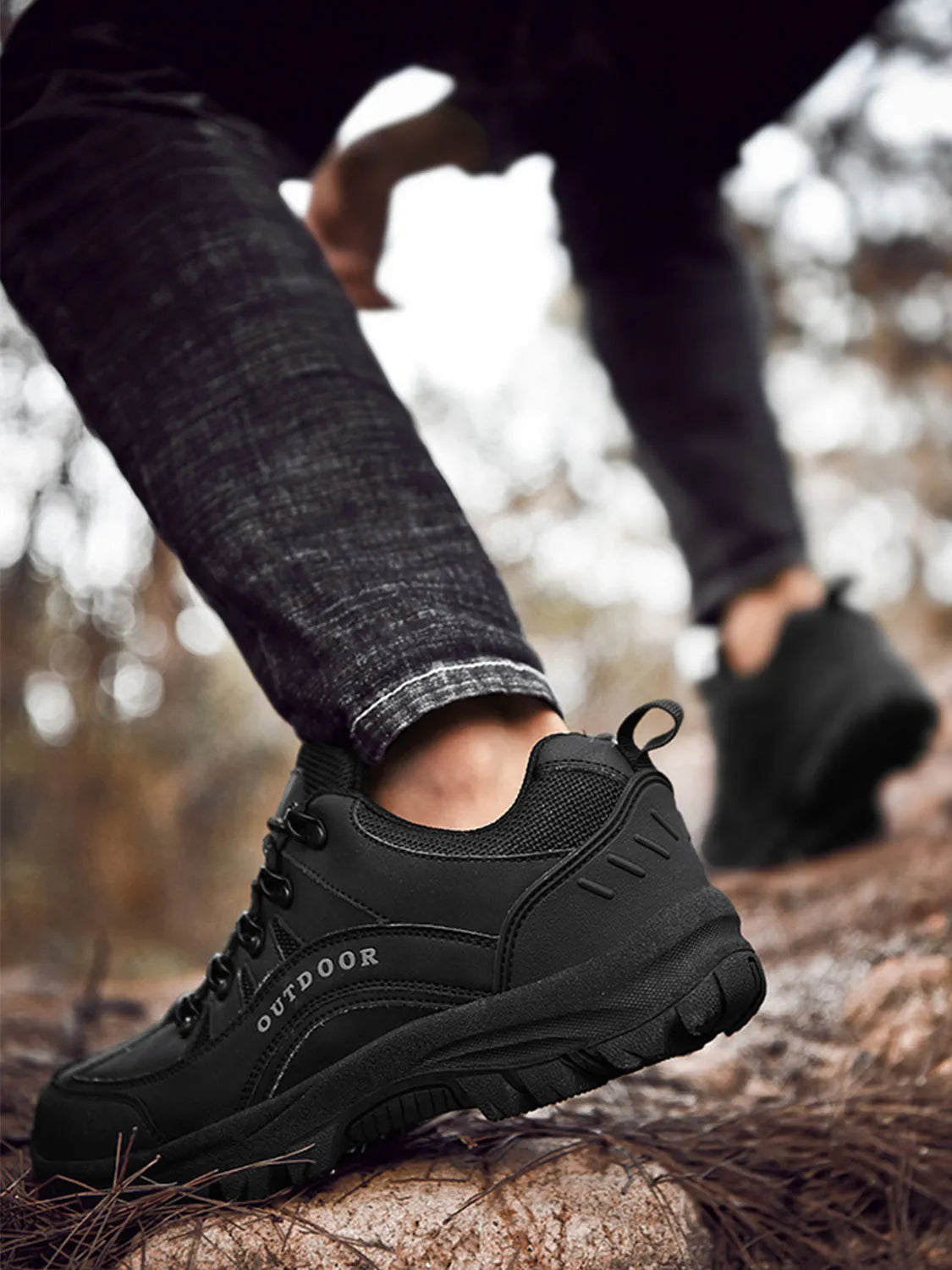 Black lace-up shoe with chunky treaded outsole, worn on a log