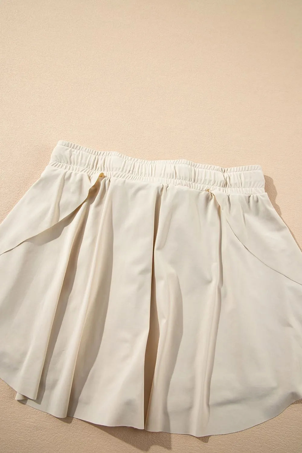Back of ivory skort showing draped overlay and high elastic waistband.