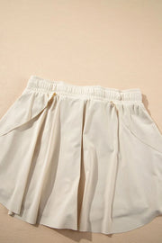 Back of ivory skort showing draped overlay and high elastic waistband.