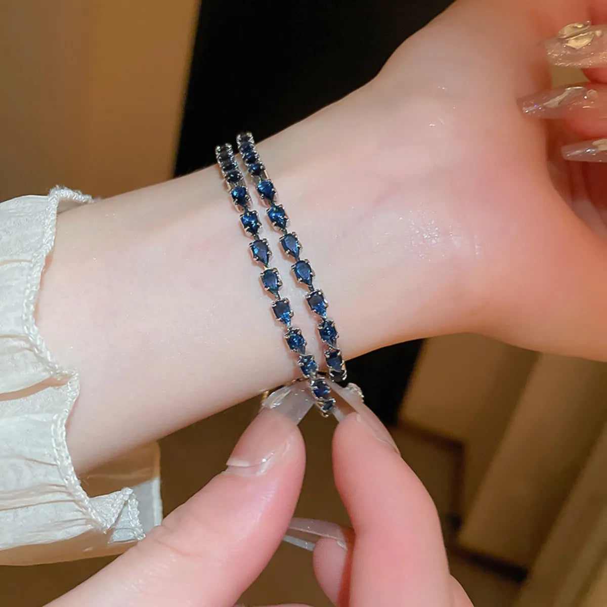 Close-up of two rows of blue stones and the dangling adjustment chain on a bracelet