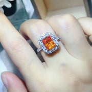 Orange center stone halo ring worn on hand