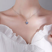 Model wearing a small blue heart pendant necklace