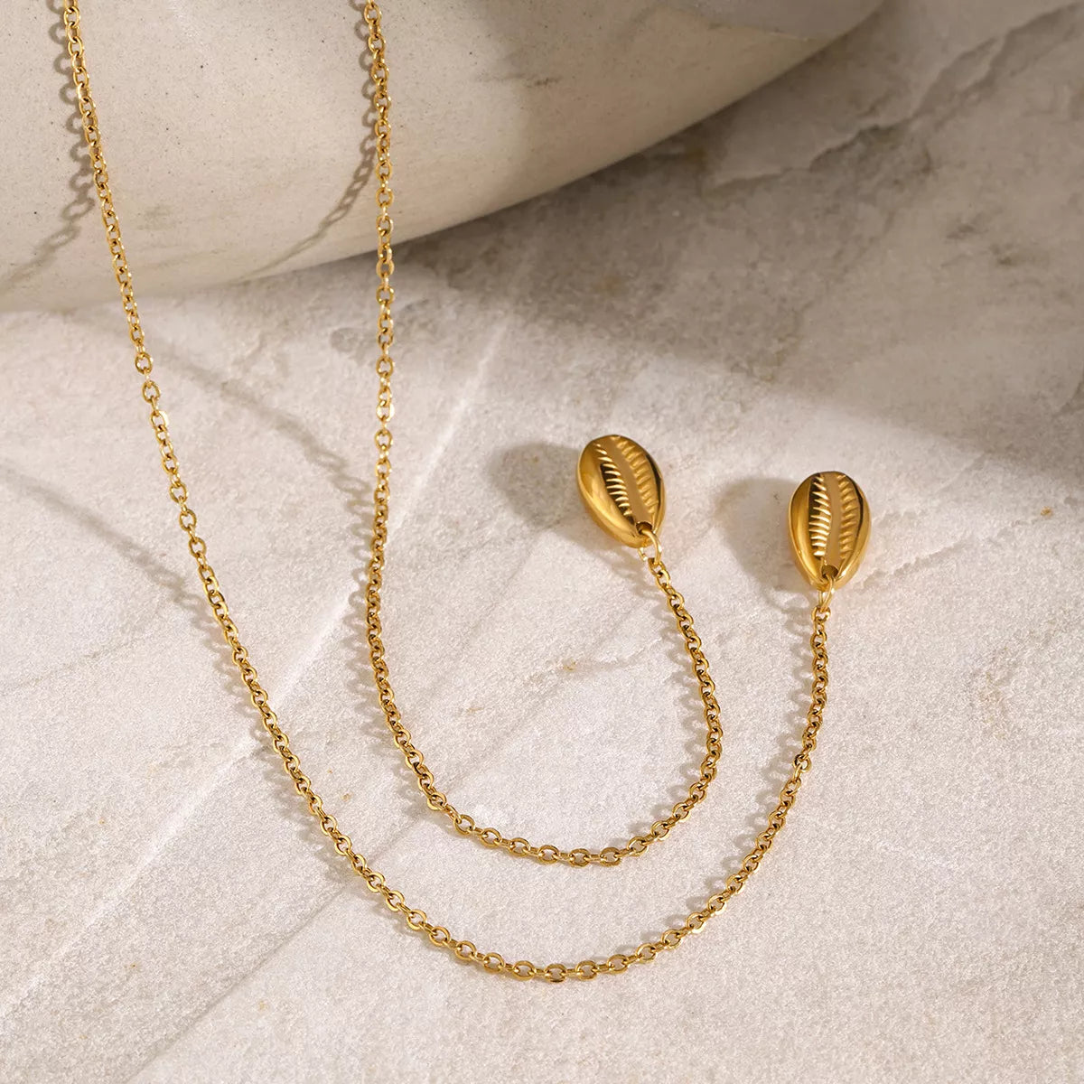 Gold Y necklace with matching oval stud earrings arranged on fabric