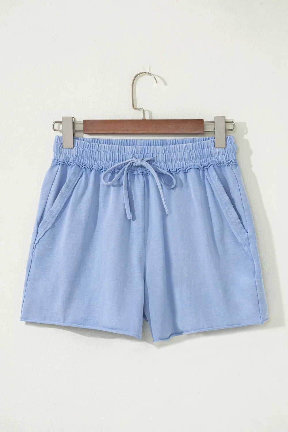 Light-blue drawstring shorts hanging from a wooden hanger