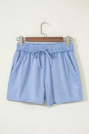 Light-blue drawstring shorts hanging from a wooden hanger