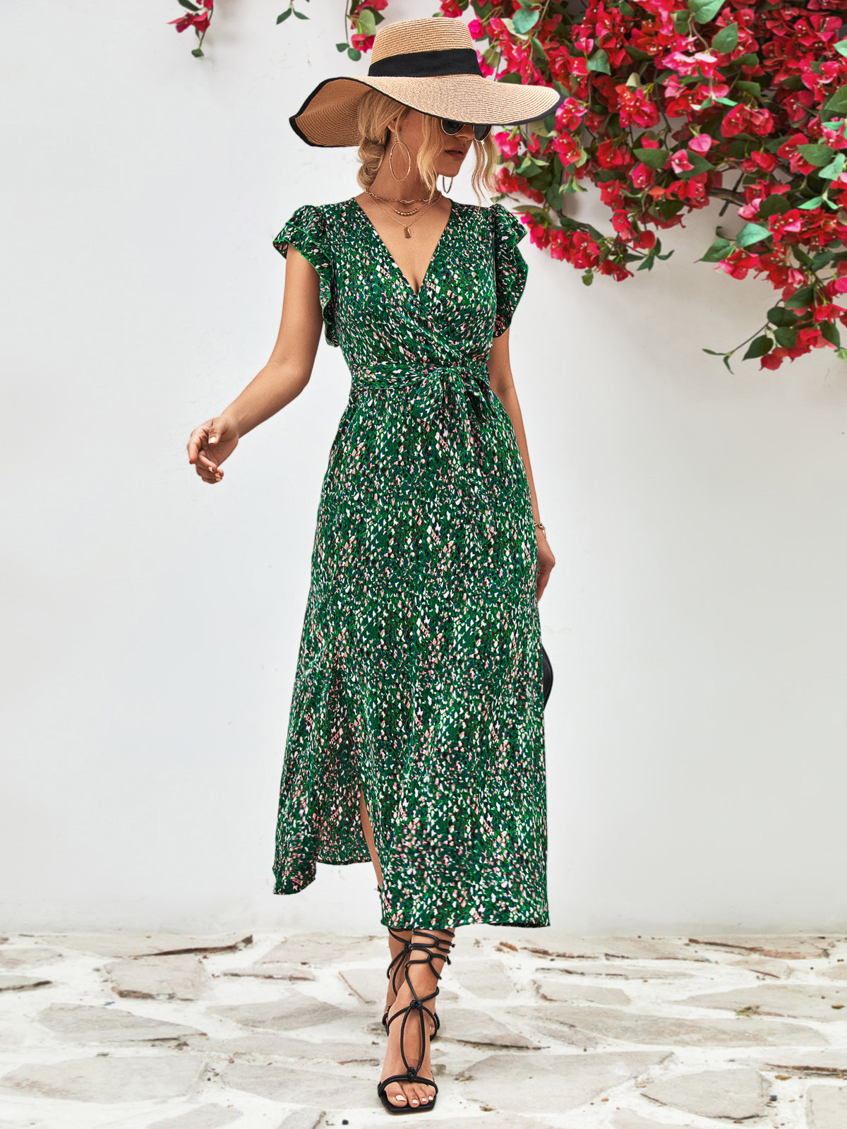 Model wearing a green printed surplice dress with flutter sleeves, front view and straw hat.
